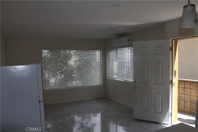 interior space with baseboards, tile patterned flooring, and a wall mounted air conditioner