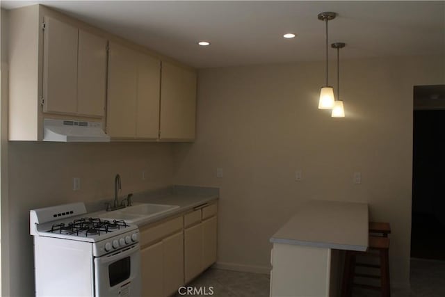 kitchen with a sink, a peninsula, white gas range oven, under cabinet range hood, and light countertops