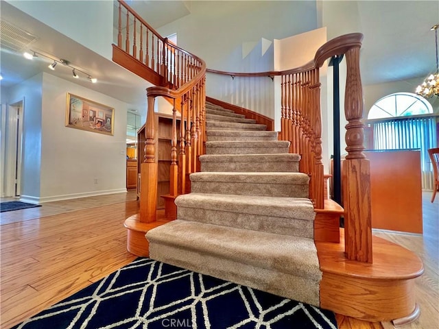 18725 Dallas Ave, Riverside, CA 92508 - staircase with wood finished floors, a high ceiling, track lighting, baseboards, and a chandelier