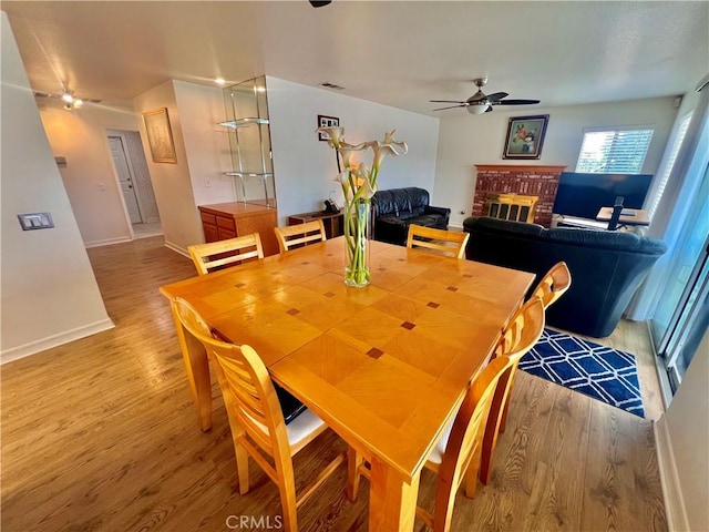 18725 Dallas Ave, Riverside, CA 92508 - dining area with light wood-style flooring, baseboards, visible vents, ceiling fan, and a brick fireplace
