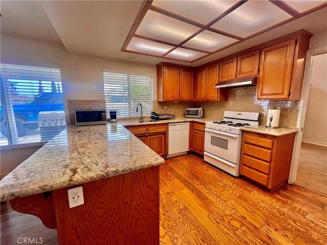 18725 Dallas Ave, Riverside, CA 92508 - kitchen with under cabinet range hood, white appliances, a sink, a peninsula, and light wood-type flooring