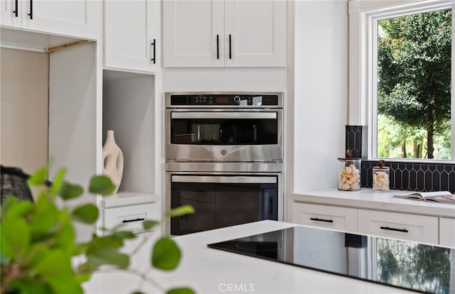 44240 La Cruz Dr, Temecula, CA 92590 - kitchen featuring white cabinetry, black electric cooktop, decorative backsplash, and stainless steel double oven