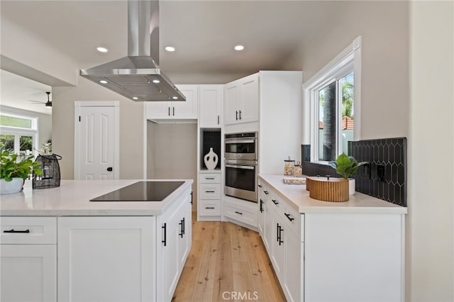 44240 La Cruz Dr, Temecula, CA 92590 - kitchen with stainless steel double oven, island range hood, black electric stovetop, and plenty of natural light