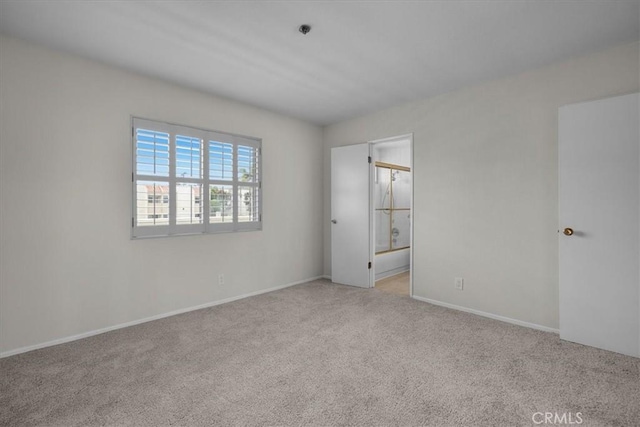 spare room featuring light colored carpet and baseboards