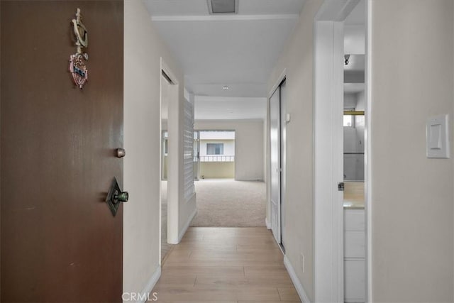 corridor with baseboards and light wood-style floors