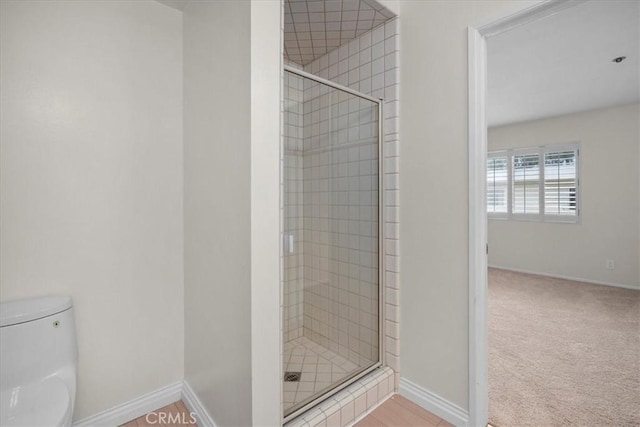 bathroom featuring a shower stall, baseboards, and toilet