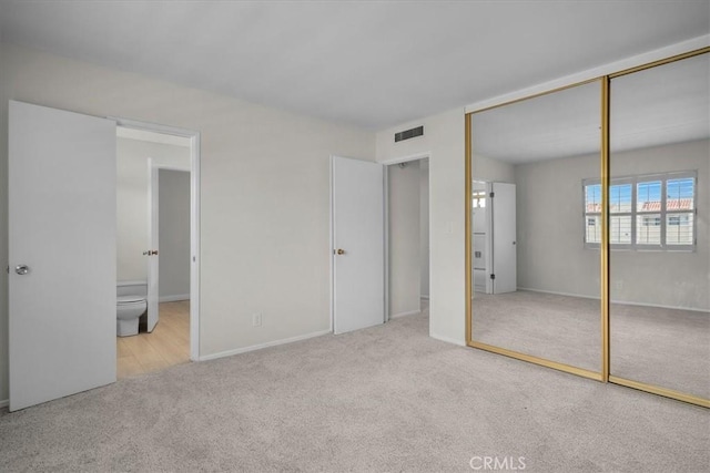 unfurnished bedroom with ensuite bath, carpet, a closet, and visible vents