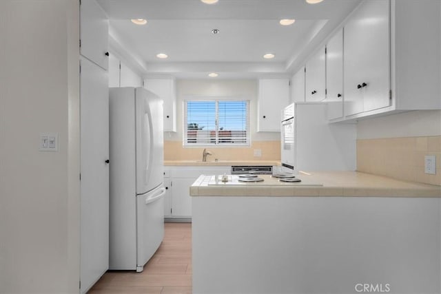kitchen with fridge, freestanding refrigerator, a peninsula, and white cabinetry