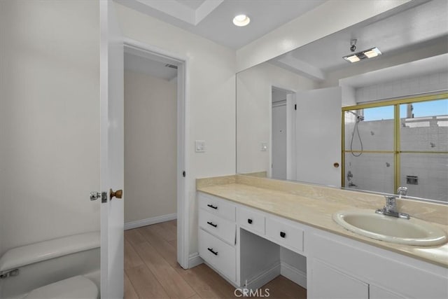 full bathroom with toilet, wood finished floors, vanity, baseboards, and tiled shower