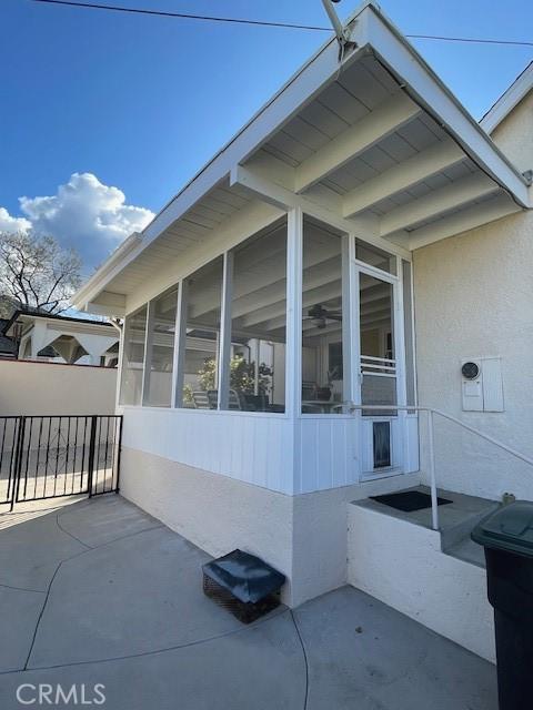 view of side of home with stucco siding and a sunroom