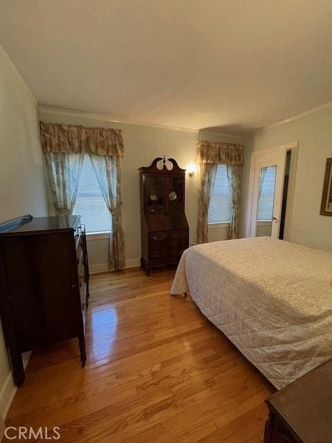 bedroom featuring light wood-type flooring, baseboards, and crown molding