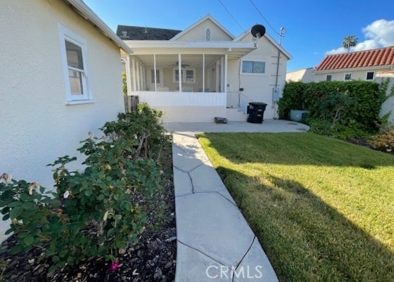 view of front facade with a sunroom, stucco siding, and a front yard