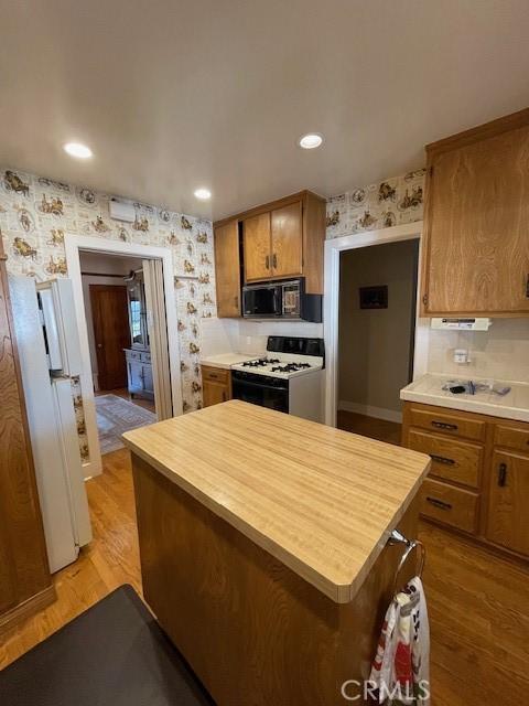 kitchen with wallpapered walls, brown cabinets, and white appliances