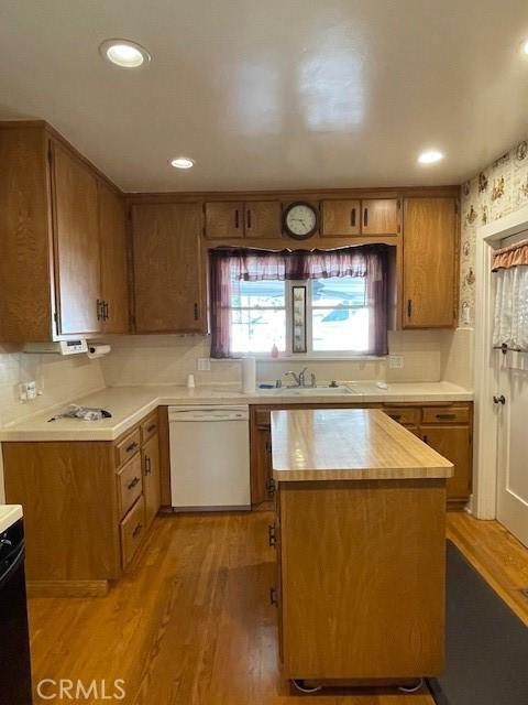 kitchen with brown cabinets, light countertops, white dishwasher, and light wood-style floors