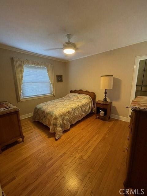 bedroom with a ceiling fan, wood finished floors, baseboards, and ornamental molding