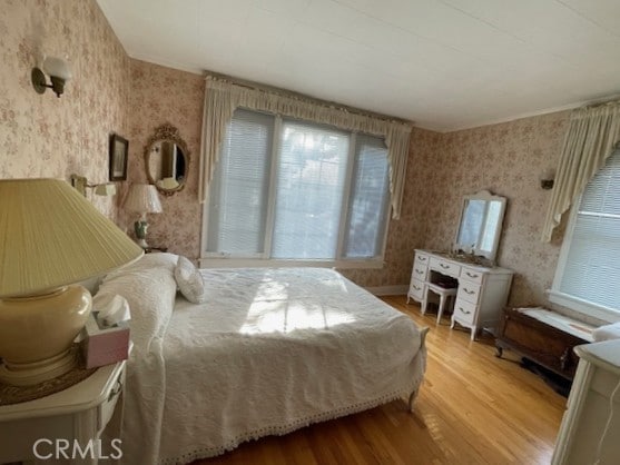 bedroom featuring wallpapered walls and wood finished floors