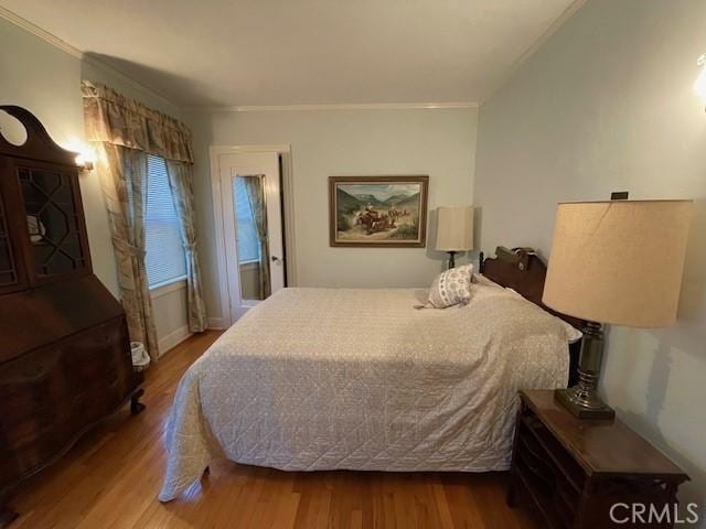 bedroom featuring ornamental molding and wood finished floors