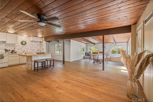 interior space featuring a ceiling fan, brick wall, light wood-style flooring, and wooden ceiling