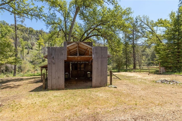 view of outbuilding featuring an outbuilding, a view of trees, and fence