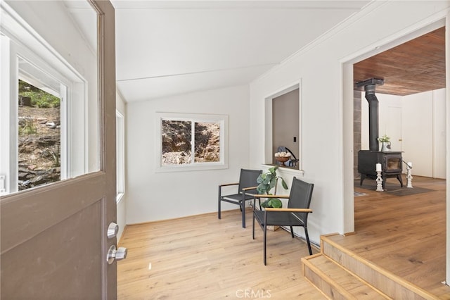 interior space with vaulted ceiling, a wood stove, and wood finished floors