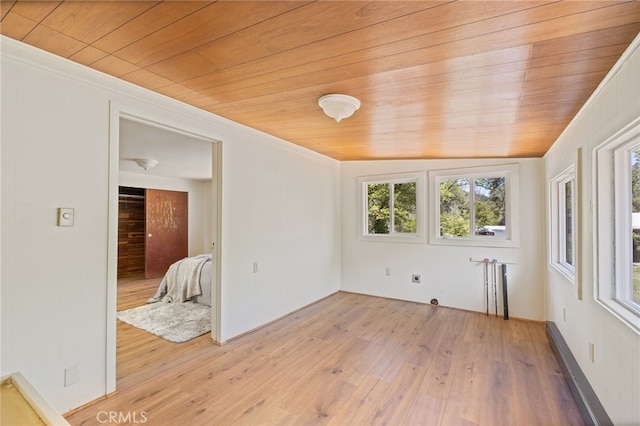 empty room with a baseboard heating unit, light wood-style floors, and wooden ceiling