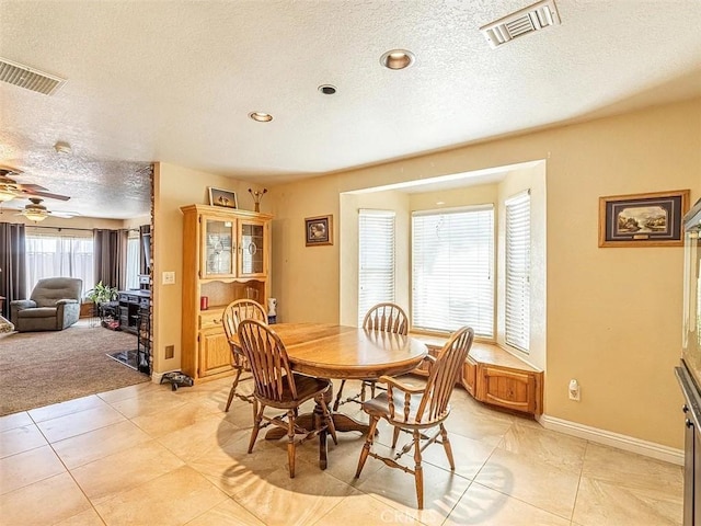 dining space featuring baseboards, light tile patterned flooring, visible vents, and a textured ceiling