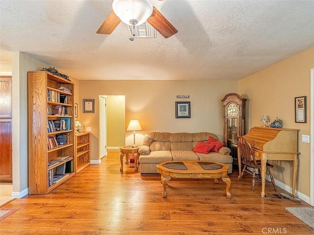 living room with a textured ceiling, baseboards, ceiling fan, and hardwood / wood-style flooring