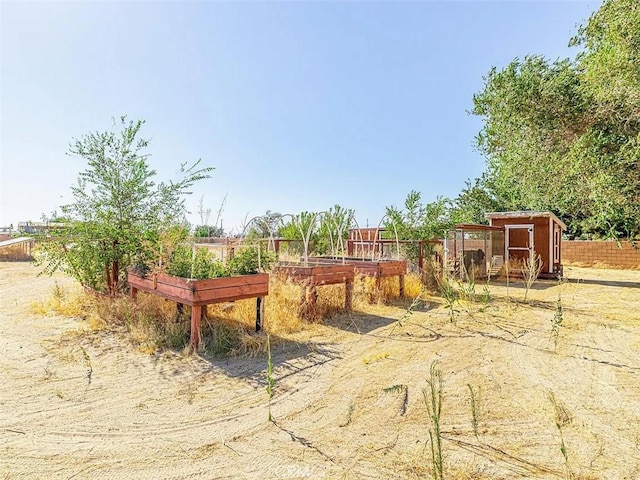 view of yard featuring an outbuilding, a garden, fence, and a storage unit