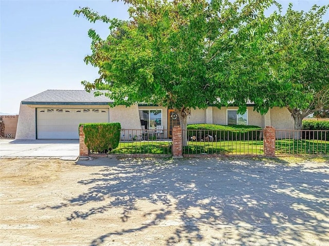 obstructed view of property with concrete driveway, stucco siding, a garage, and fence private yard