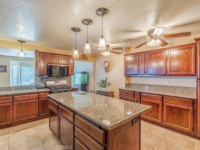 kitchen with stainless steel gas range oven, a center island, a textured ceiling, ceiling fan, and black microwave