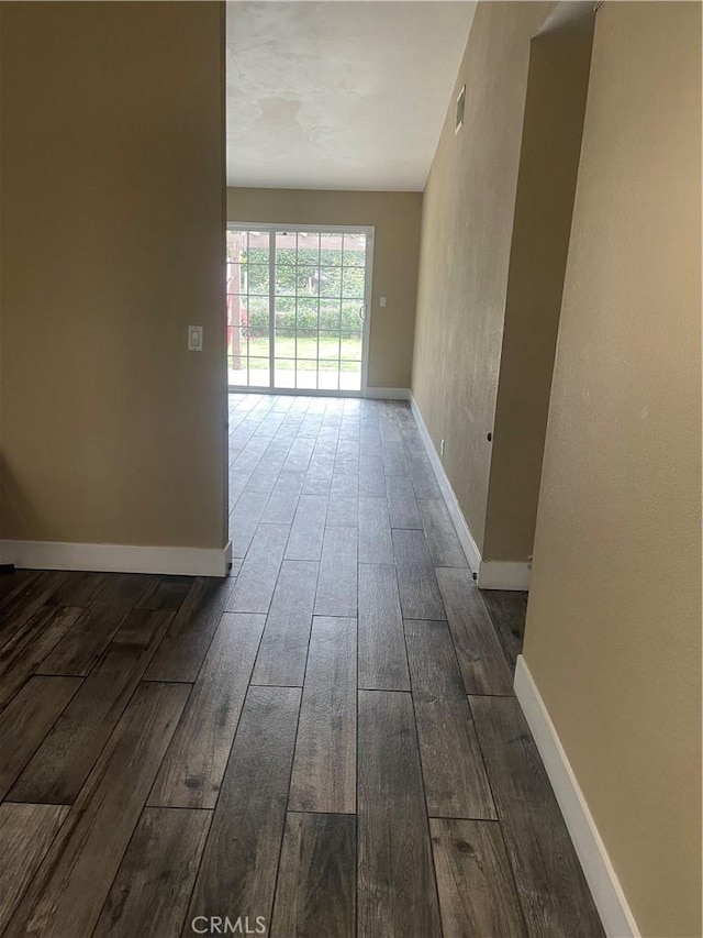 spare room featuring baseboards, visible vents, and wood finished floors