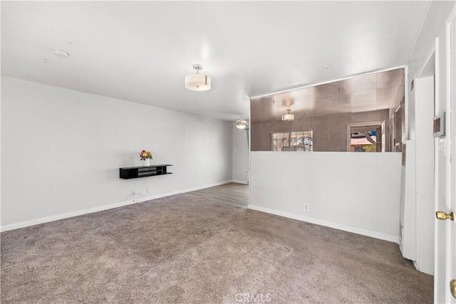 below grade area with carpet floors, a ceiling fan, and baseboards