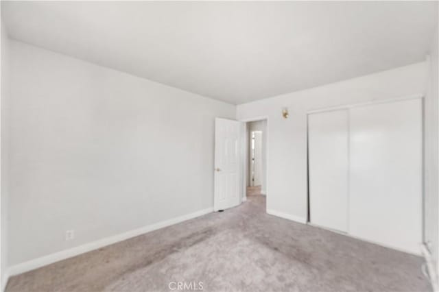 unfurnished bedroom featuring carpet, a closet, and baseboards