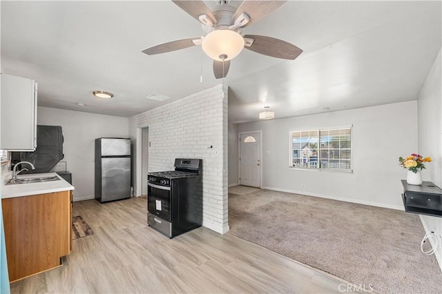 kitchen featuring freestanding refrigerator, baseboards, gas stove, a sink, and light countertops