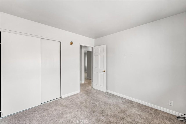 unfurnished bedroom featuring baseboards, carpet flooring, and a closet