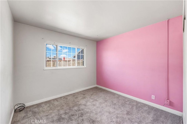 carpeted empty room featuring baseboards