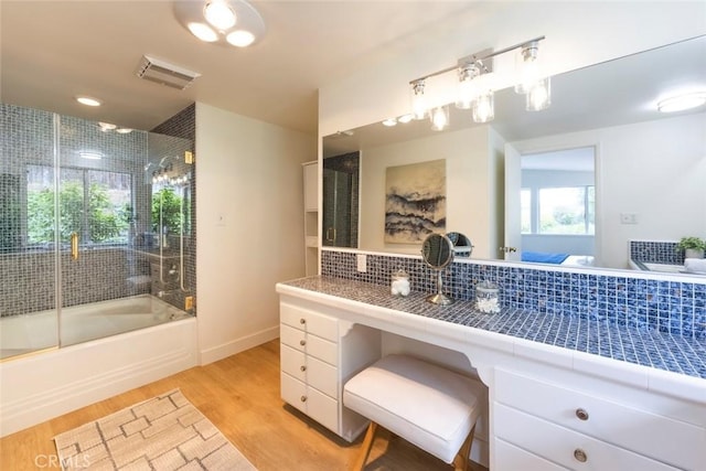 full bath with baseboards, visible vents, decorative backsplash, wood finished floors, and combined bath / shower with glass door