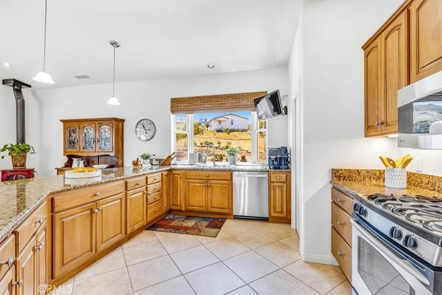 kitchen featuring light tile patterned floors, brown cabinetry, light stone countertops, decorative light fixtures, and appliances with stainless steel finishes