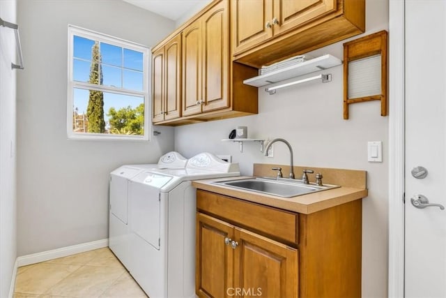 laundry room featuring a sink, washer and clothes dryer, cabinet space, light tile patterned flooring, and baseboards