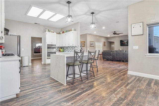 6748 Coriander Dr, Oak Hills, CA 92344 - kitchen with a peninsula, white cabinetry, dark wood-type flooring, and appliances with stainless steel finishes