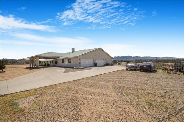 6748 Coriander Dr, Oak Hills, CA 92344 - view of home's exterior featuring a chimney, driveway, a mountain view, and a garage