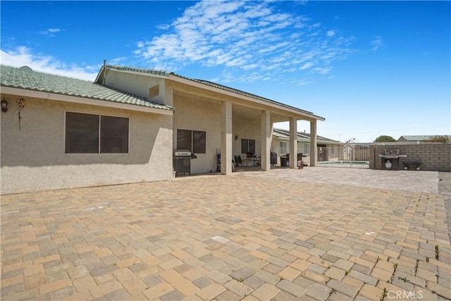 6748 Coriander Dr, Oak Hills, CA 92344 - rear view of house featuring a fenced in pool, fence, a patio, stucco siding, and a tile roof