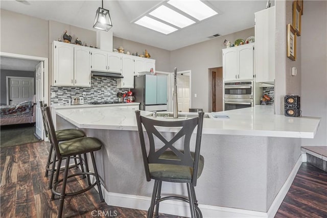 6748 Coriander Dr, Oak Hills, CA 92344 - kitchen with a peninsula, visible vents, dark wood-style flooring, white cabinets, and appliances with stainless steel finishes