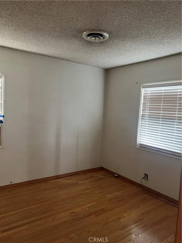 unfurnished room with baseboards, light wood-style flooring, and a textured ceiling