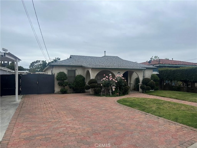 single story home with a gate, roof with shingles, driveway, stucco siding, and a front yard