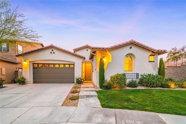 mediterranean / spanish-style home featuring stucco siding, an attached garage, concrete driveway, a lawn, and a tile roof
