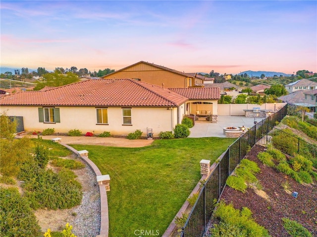 back of house at dusk featuring an outdoor living space with a fire pit, stucco siding, a patio area, and a tiled roof
