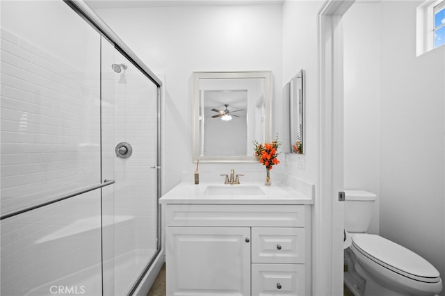 bathroom featuring a stall shower, vanity, toilet, and a ceiling fan