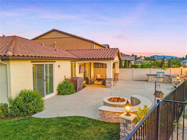 back of house with an outdoor living space with a fire pit, a patio, a fenced backyard, and exterior kitchen