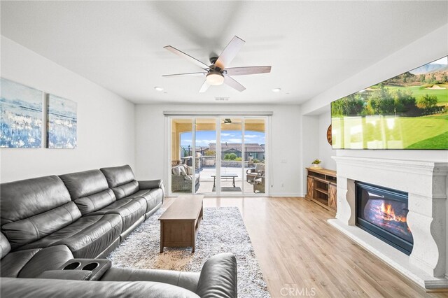 living area featuring light wood-style floors, ceiling fan, a glass covered fireplace, and recessed lighting